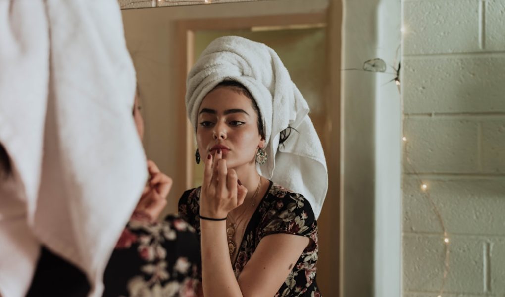 woman putting makeup in front of mirror