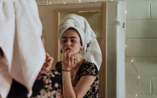 woman putting makeup in front of mirror