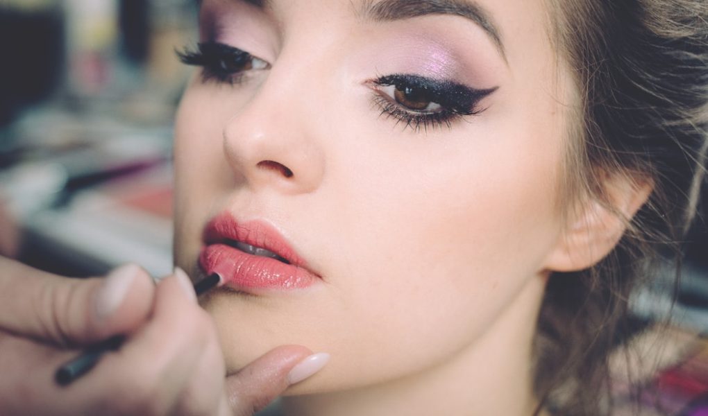 woman getting lips applied with lipstick