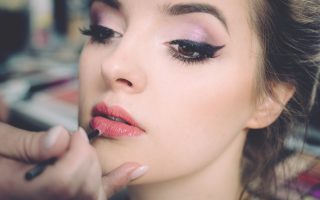 woman getting lips applied with lipstick